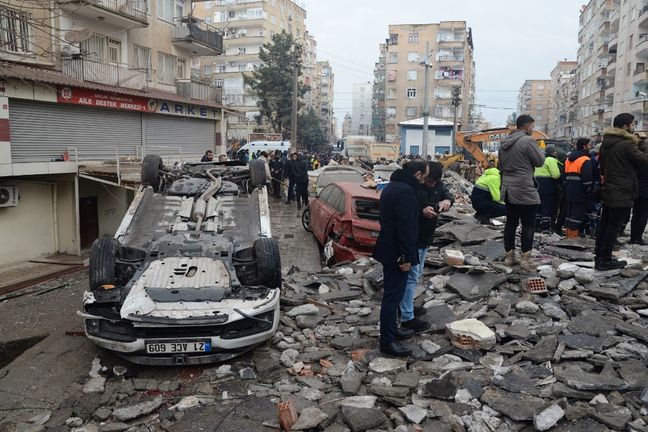 Neighborhood residents search for survivors in the rubble in Diyarbakir on February 6, 2023, after the 7.8 magnitude earthquake hit southeastern Turkey.