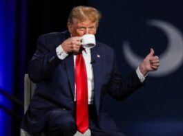 Donald Trump drinks coffee with a thumbs up.