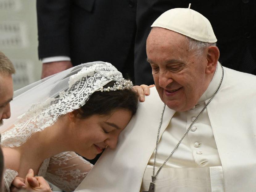 Pope Francis smiles at a newly married woman.
