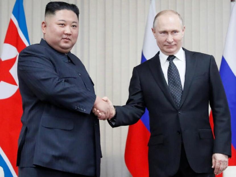Vladimir Putin shakes hands with Kim Jung Un.
