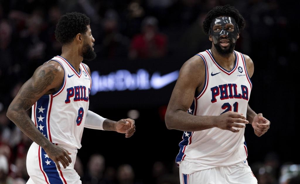 Philadelphia 76ers forward Paul George, left, and center Joel Embiid runs back against the Portland Trail Blazers during the second half of an NBA basketball game, Monday, Dec. 30, 2024, in Portland, Ore. (AP Photo/Howard Lao)