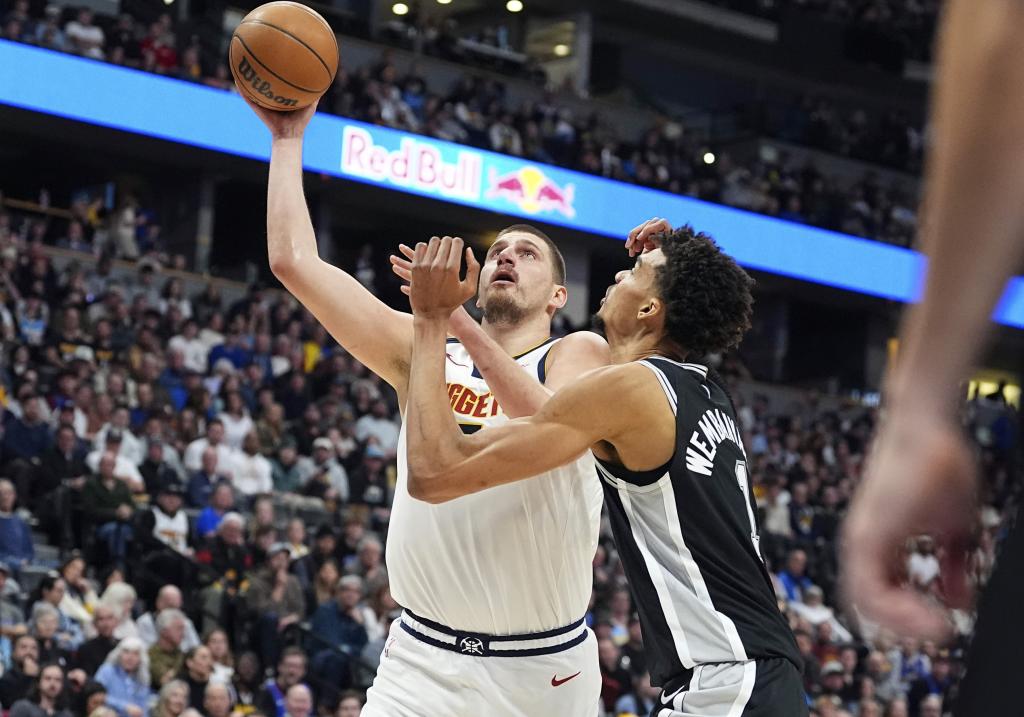 Denver Nuggets center Nikola Jokic, left, goes up for a basket as San Antonio Spurs center Victor Wembanyama defends in the first half of an NBA basketball game Friday, Jan. 3, 2025, in Denver. (AP Photo/David Zalubowski)