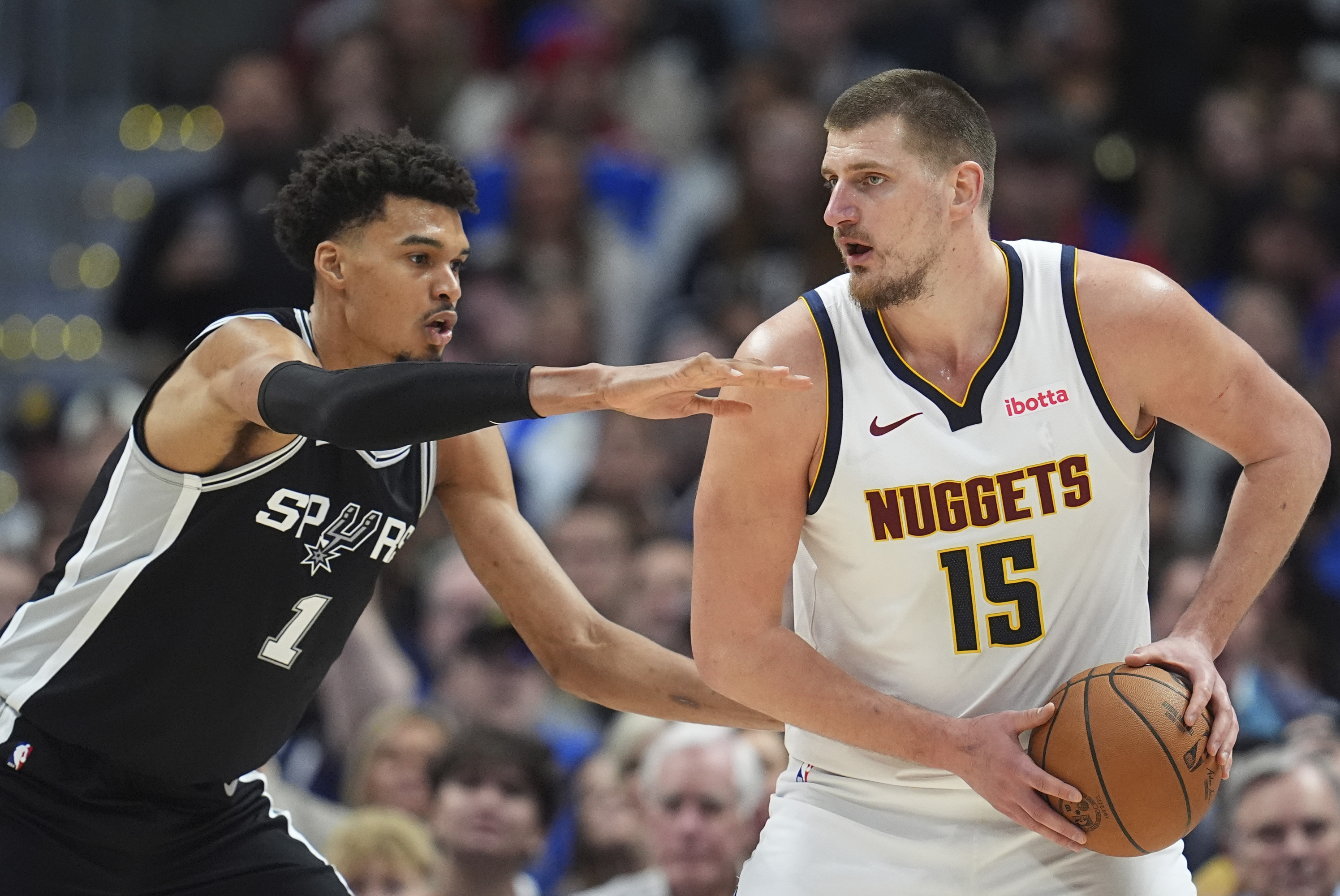 Denver Nuggets center Nikola Jokic, right, looks to pass the ball as San Antonio Spurs center Victor Wembanyama defends in the second half of an NBA basketball game Friday, Jan. 3, 2025, in Denver. (AP Photo/David Zalubowski)