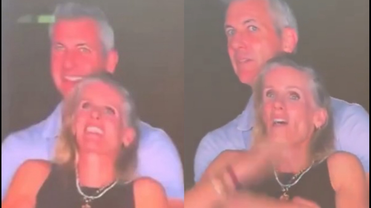 A couple reacts awkwardly to being shown on a stadium 'kiss cam' screen.