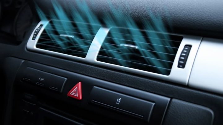 A person's hand adjusting a car's air conditioning dial.