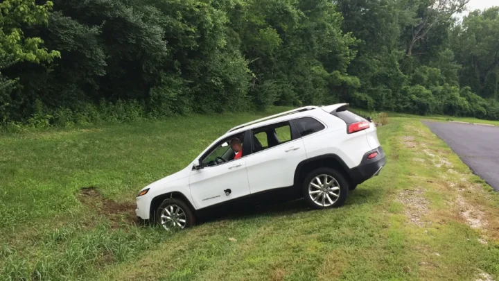 A person's hand interacting with a car's touchscreen, displaying various apps and functions.