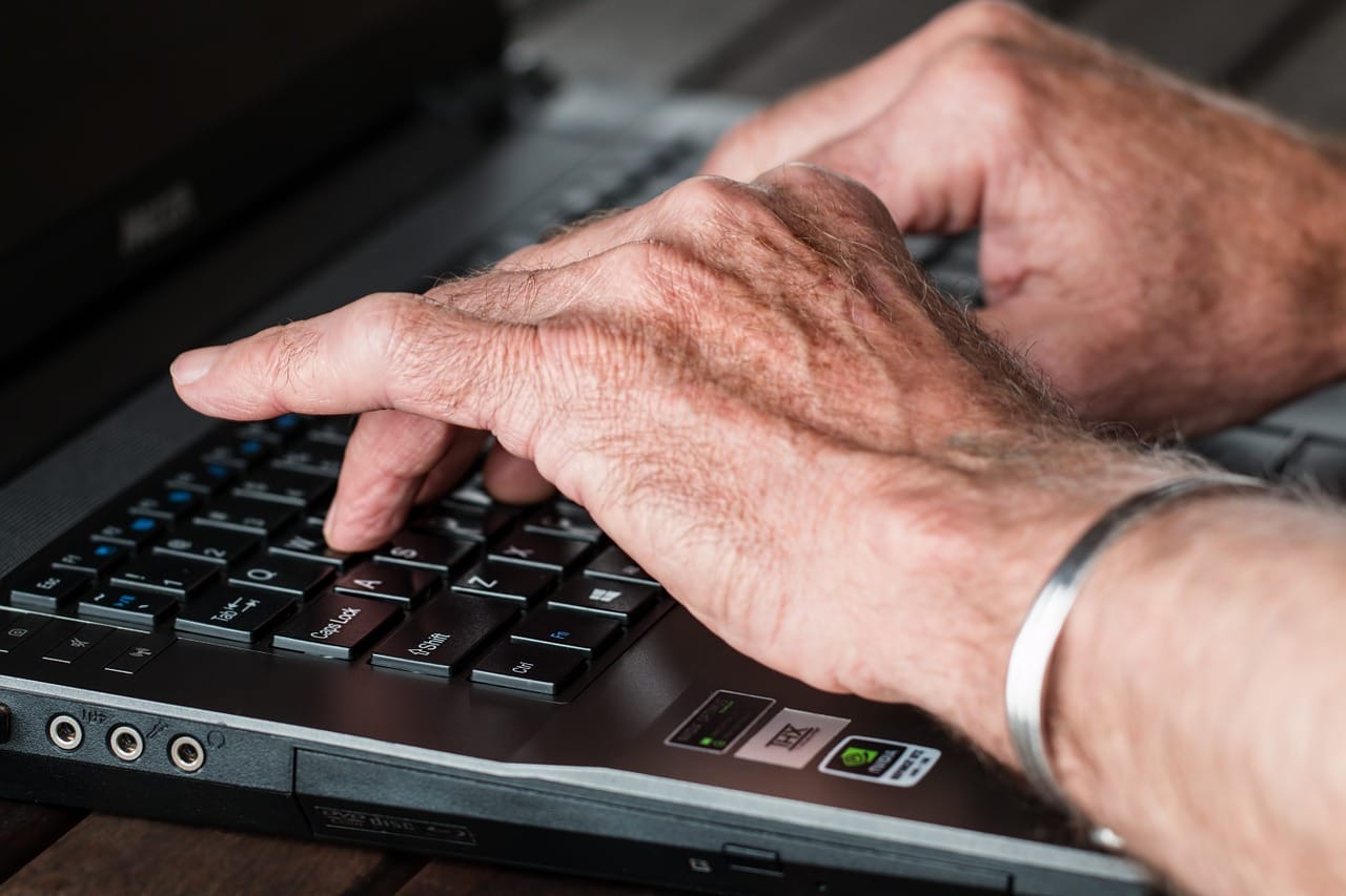 A person's hands on a laptop keyboard, representing online activity.